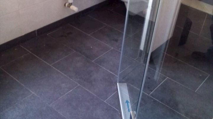 Gerenoveerde badkamer met antracietkleurige vloertegels en een RVS douchegoot